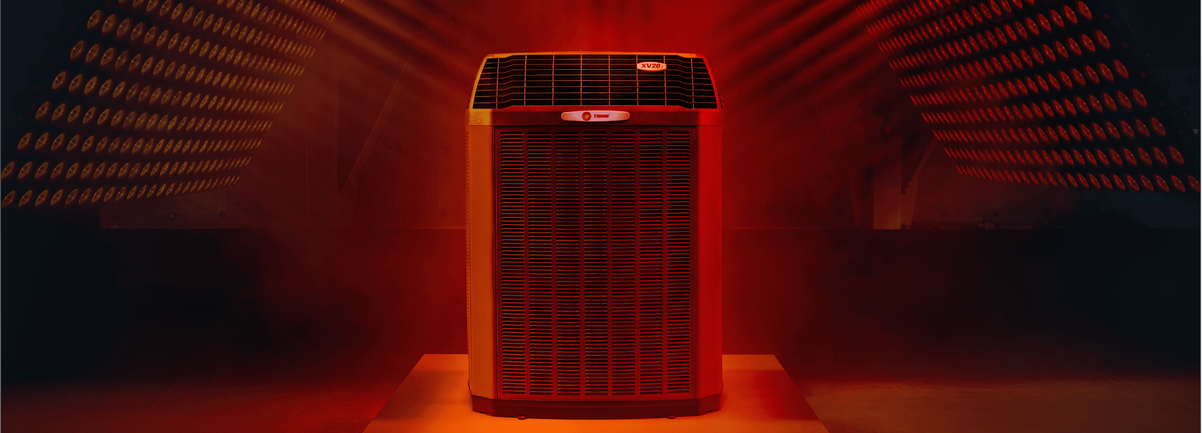 A Trane indoor unit is displayed on a platform in a room with red lights and fog.