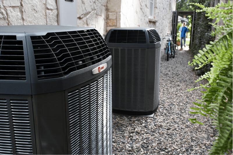 Outdoor HVAC units on a gravel pathway with a bike in the background.