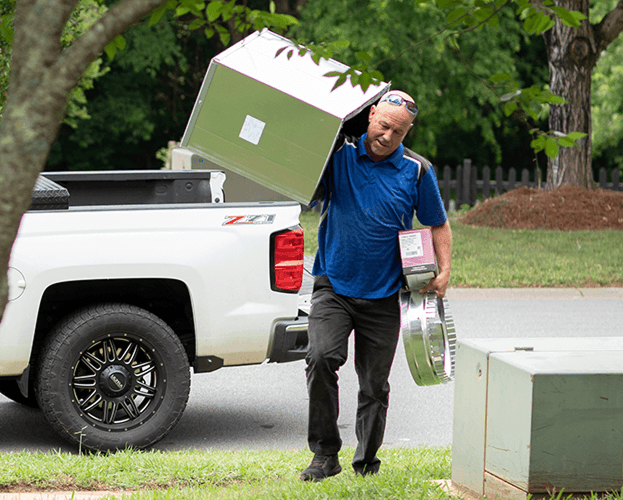 A Trane technician is carrying a gas furnace unit.