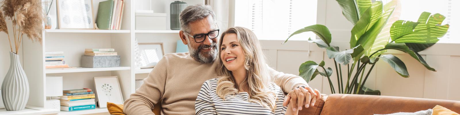 A couple is cuddling on their cream colored couch.
