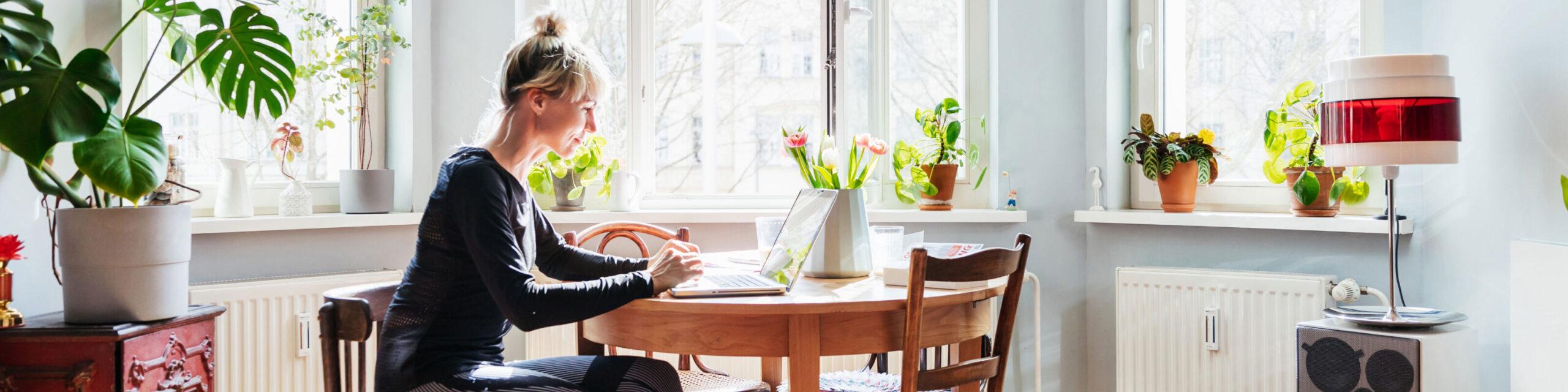A woman seated at a table searching on laptop.