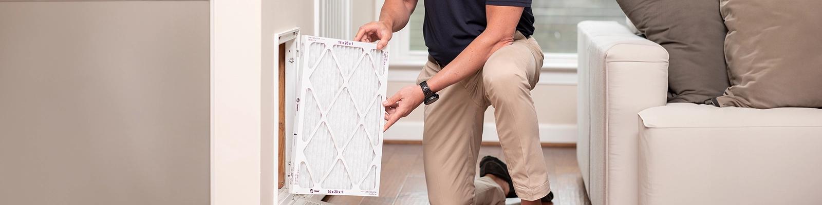 A Trane technician is replacing an air filter.
